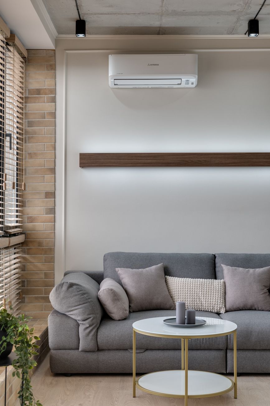 Climatisation murale réversible installée au-dessus du canapé dans un séjour contemporain